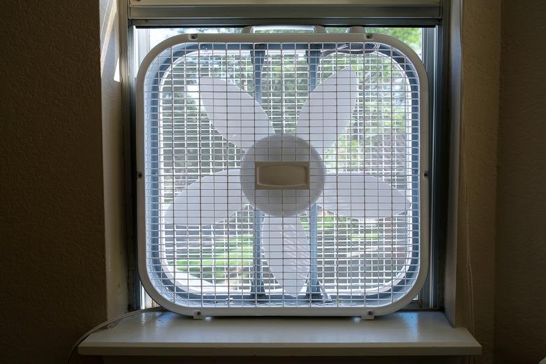 Classic window box fan inserted in home room window indoor cooling air conditioning vetilation equipment. front view hight quality close up photo