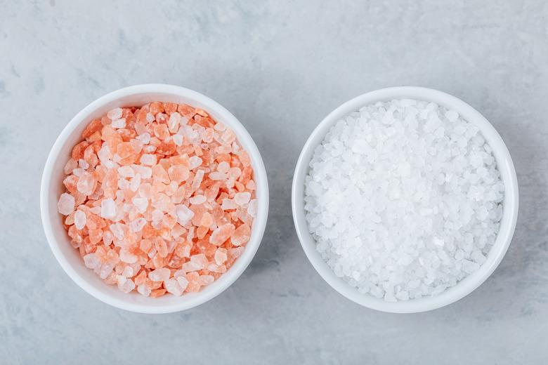 Himalayan Crystal Salt in white bowls on gray stone background.