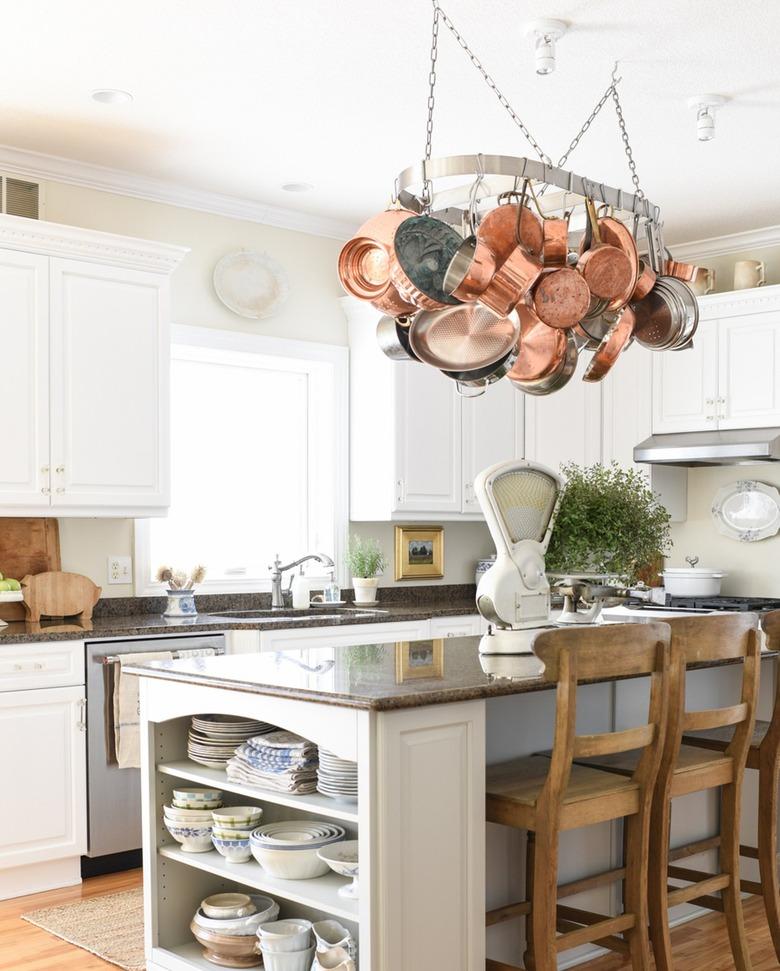 farmhouse kitchen with copper cookware hanging above island