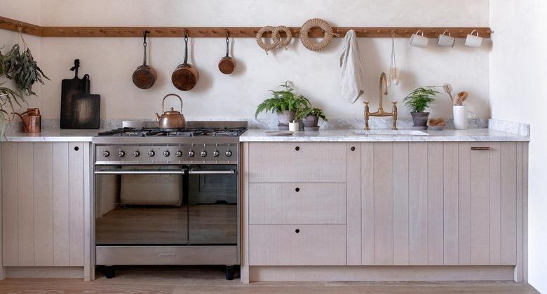 Modern kitchen with wood dowels and hanging copper pots.