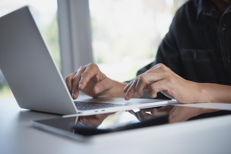 Businessman working laptop computer, surfing the internet with digital tablet on the table at home office. Working at home, telecommuting concept