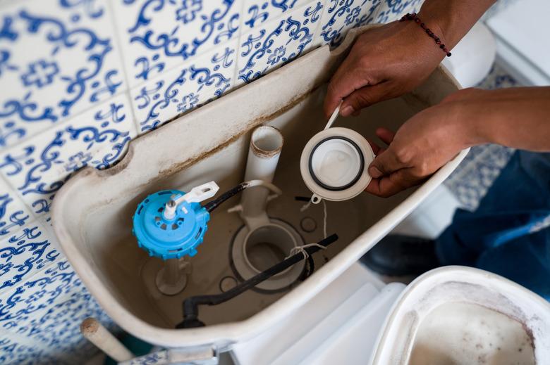 Close-up on a plumber fixing a toilet in the bathroom