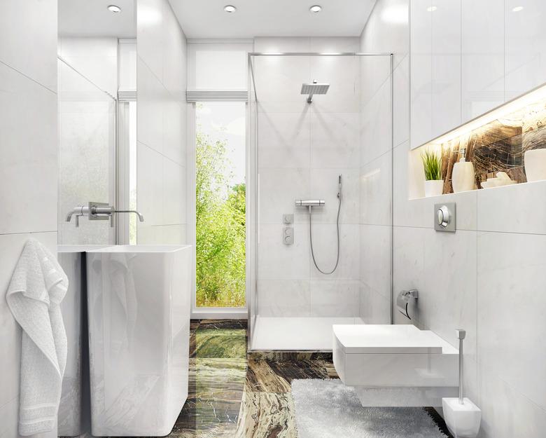 Modern white bathroom with toilet, sink, shower and window.