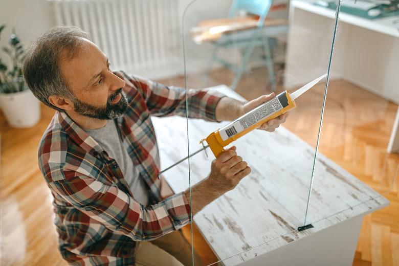 Man caulking a glass partition.