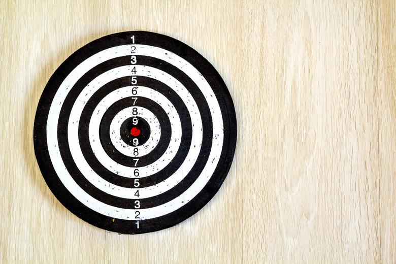 Black and white target dart on wooden background. Top view.