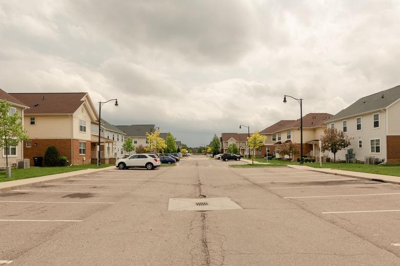 a view down a street flanked by two-story houses made of brick on the bottom and yellow siding on top