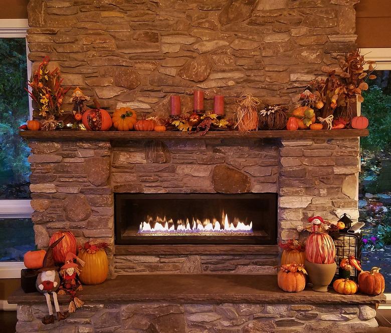 Large, Rustic Stone Fireplace All Glowing with Soothing Flames with Pumpkins and Autumn Holiday Decor