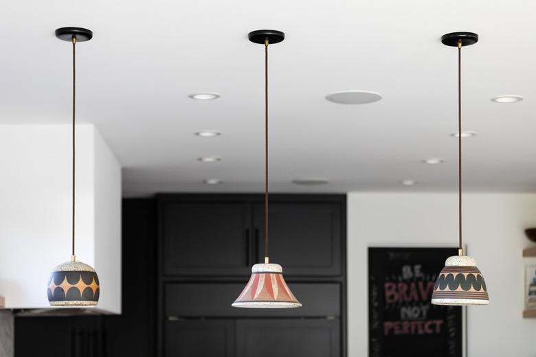 Pendant lights with multicolored shades in a white-walled kitchen