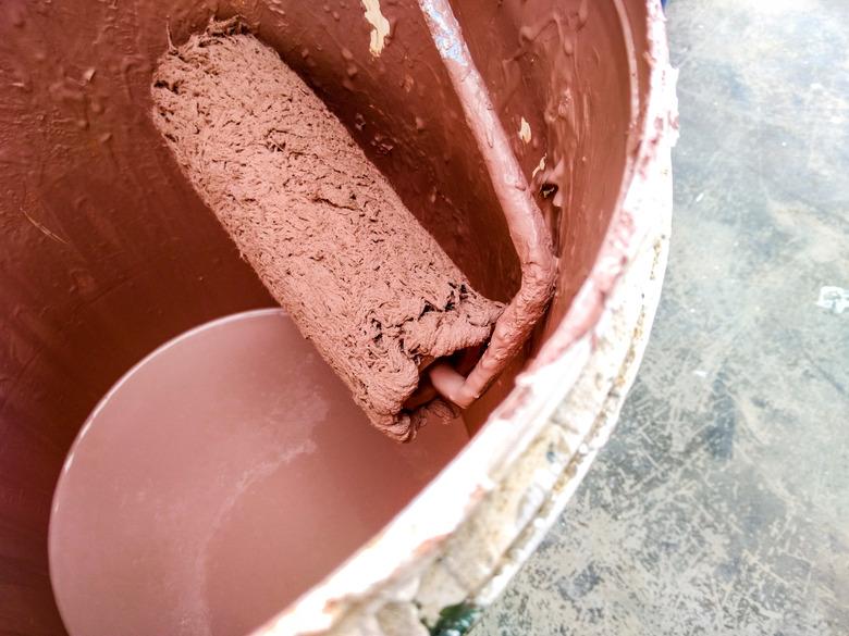 A paint roller in a bucket of paint.