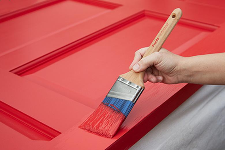 Painting a door with a paintbrush.