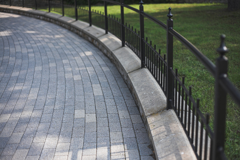 Wrought-iron fence and curved stone driveway.