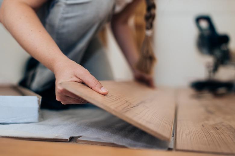 Woman installing laminate flooring.