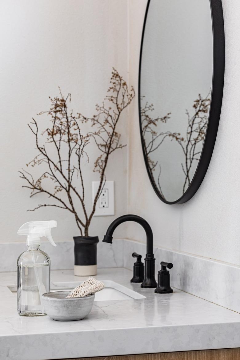 A marble countertop with black faucet and cleaning supplies sitting on the counter