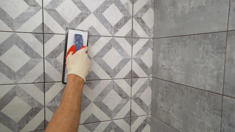 Black grout for tiles. laying ceramic tiles. Tilers fill the spaces between tiles with a rubber trowel. Grout in the bathroom.