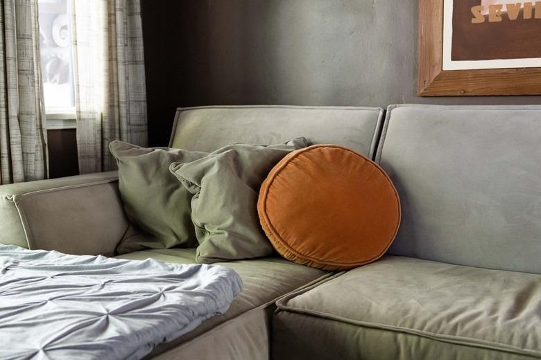 grey microfiber couch with orange round pillow