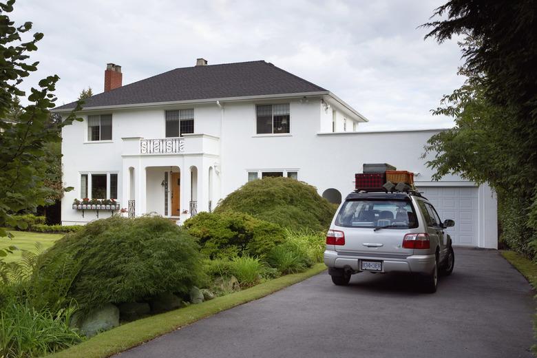 Sports utility vehicle parked in front drive of house, loaded with luggage