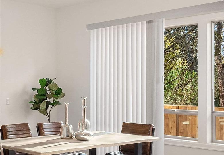 Modern white dining room with vertical blinds and houseplant.