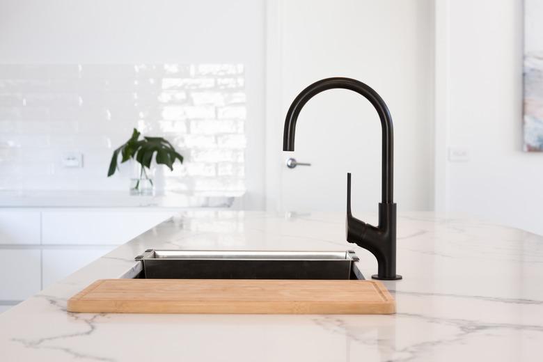 Monochrome kitchen detail of black gooseneck tap