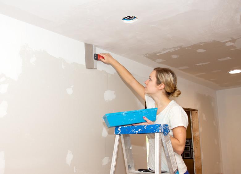 Woman Taping Ceiling Joint. Kitchen Remodel.