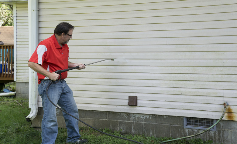 Contractor Using A Pressure Washer To Clean Vinyl Siding