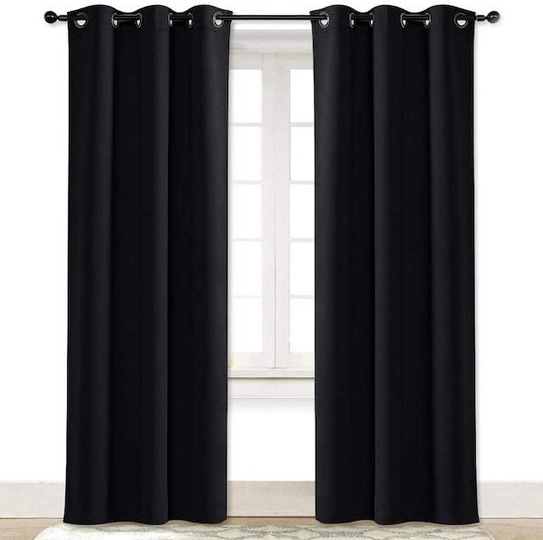 Black soundproof curtains hung up over a window