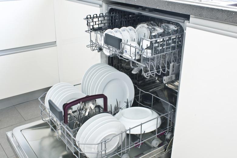 Open dishwasher with clean dishes in the white kitchen