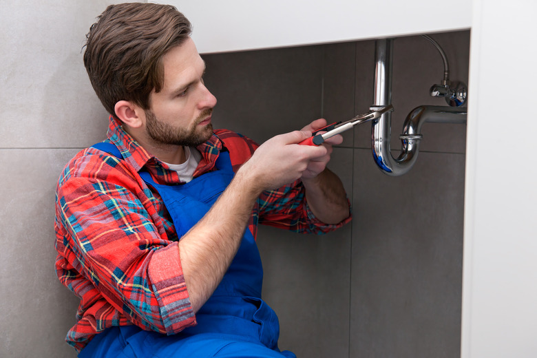 Plumber in blue overalls working on pipes