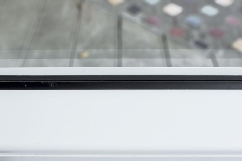 Closeup of a fixed window on a painted aluminum or pvc frame with a rubber gasket or seal.