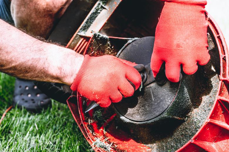 Man exchanges the mower's knife with a new one.