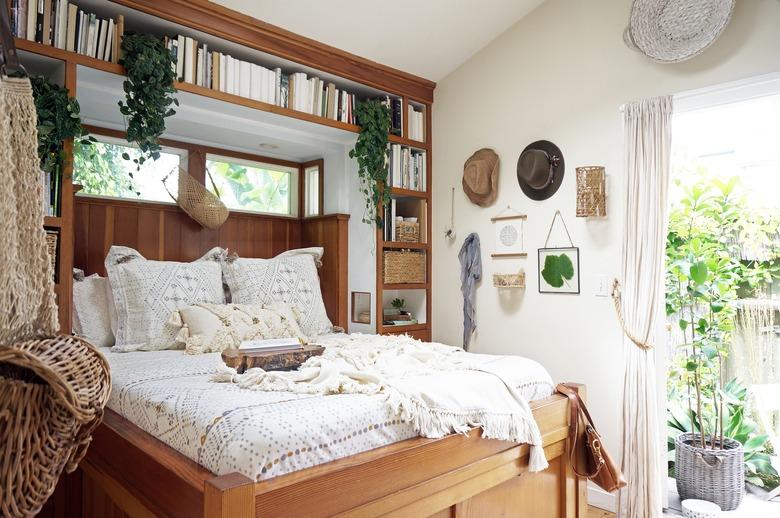 small bohemian bedroom with built-in open shelving and wood bed frame