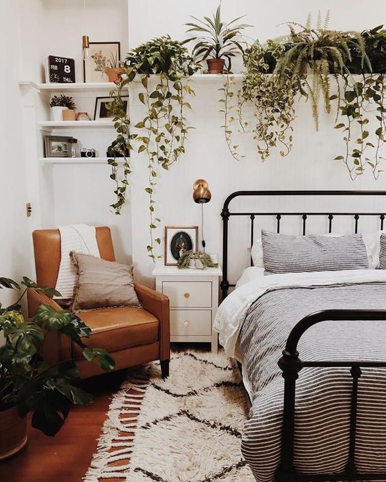 bohemian bedroom with lush greenery and leather lounge chair