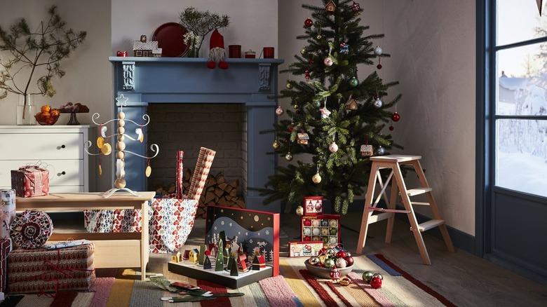 Decorated Christmas tree next to a blue fireplace surrounded by wrapping paper and presents.