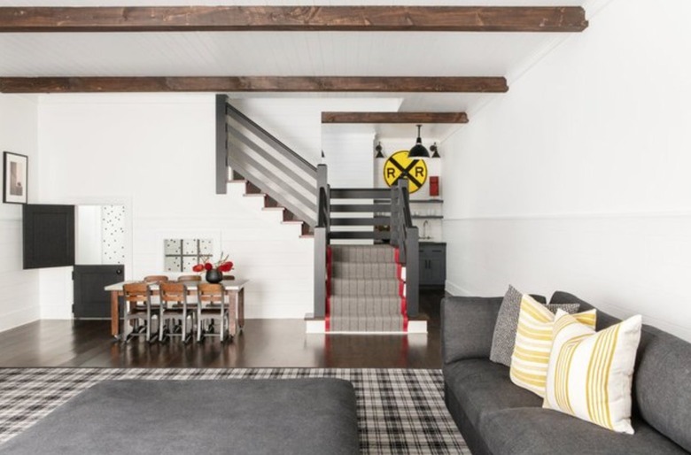 Basement with wood beam ceilings, couch, dining area.