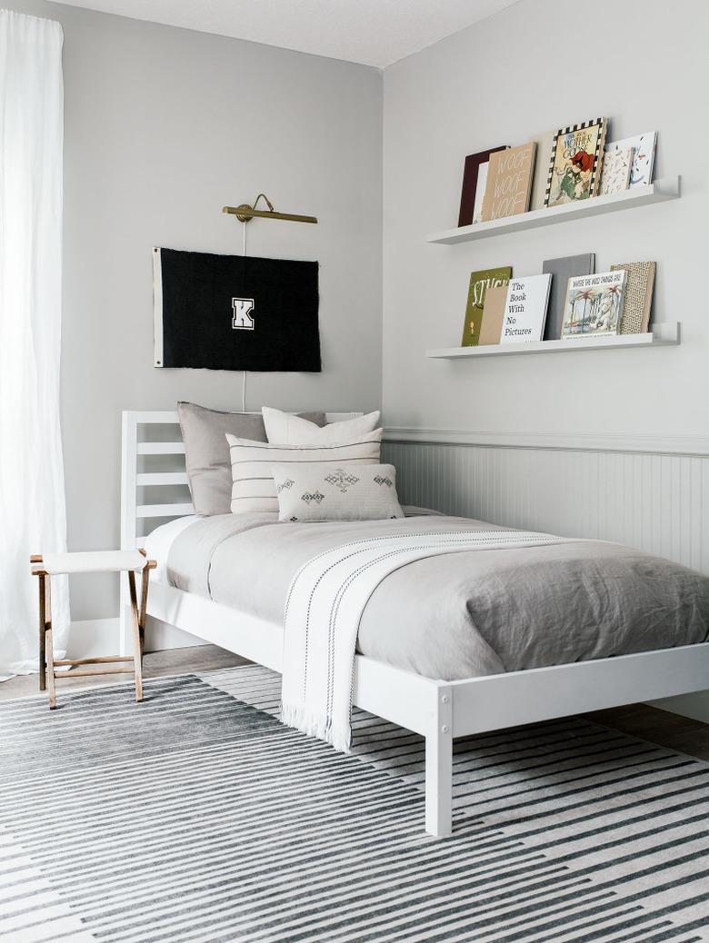 Kids' minimalist bedroom with flag decor and books on open shelving