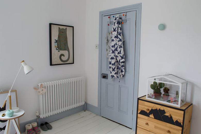 Kids' minimalist bedroom with blue door and cat wall art