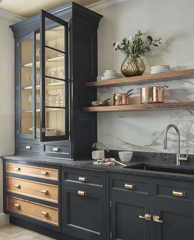 Kitchen with black cabinets, floating shelves and marble backsplash.