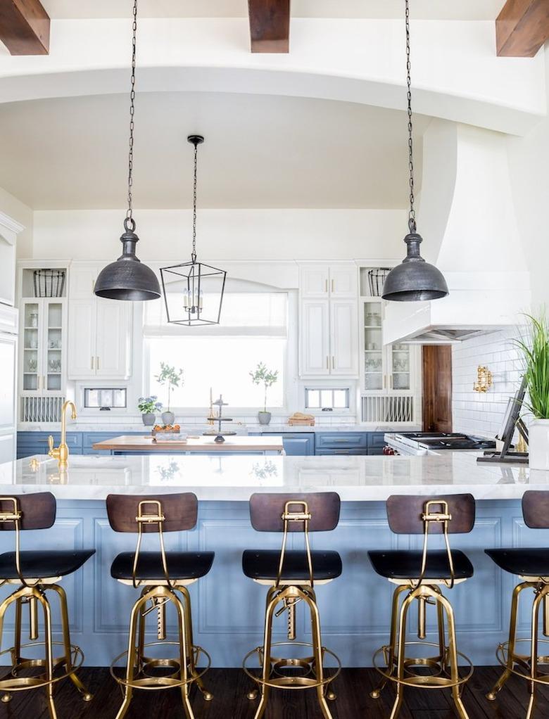 Bright kitchen with light blue island, white cabinets and wood beams on the ceiling.