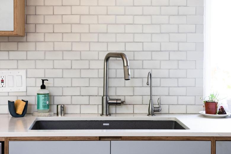 close up of kitchen sink with subway tile backsplash