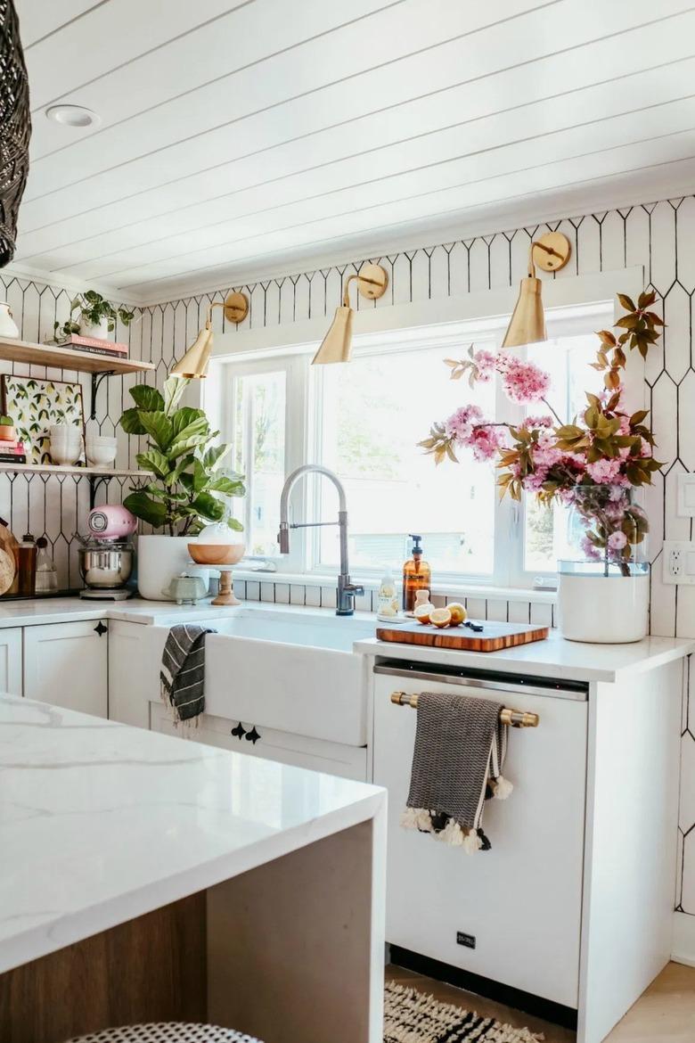 modern brass wall sconces in kitchen with white tile backsplash