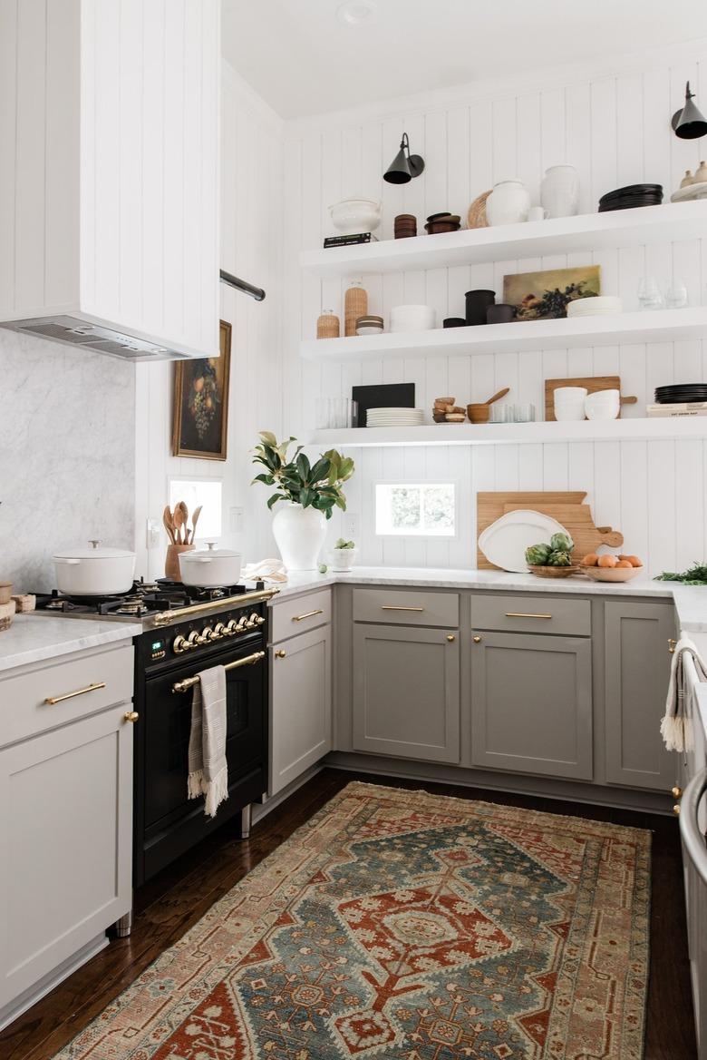 black industrial wall sconces hung over white open kitchen shelving