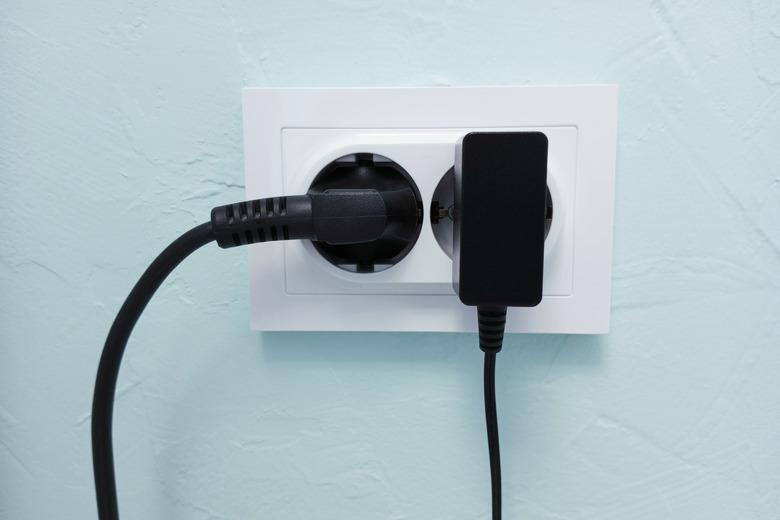 White electrical socket on  wall with electrical appliances turned on.