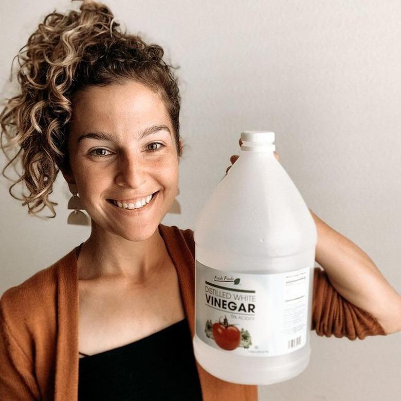 woman holding jug of white vinegar