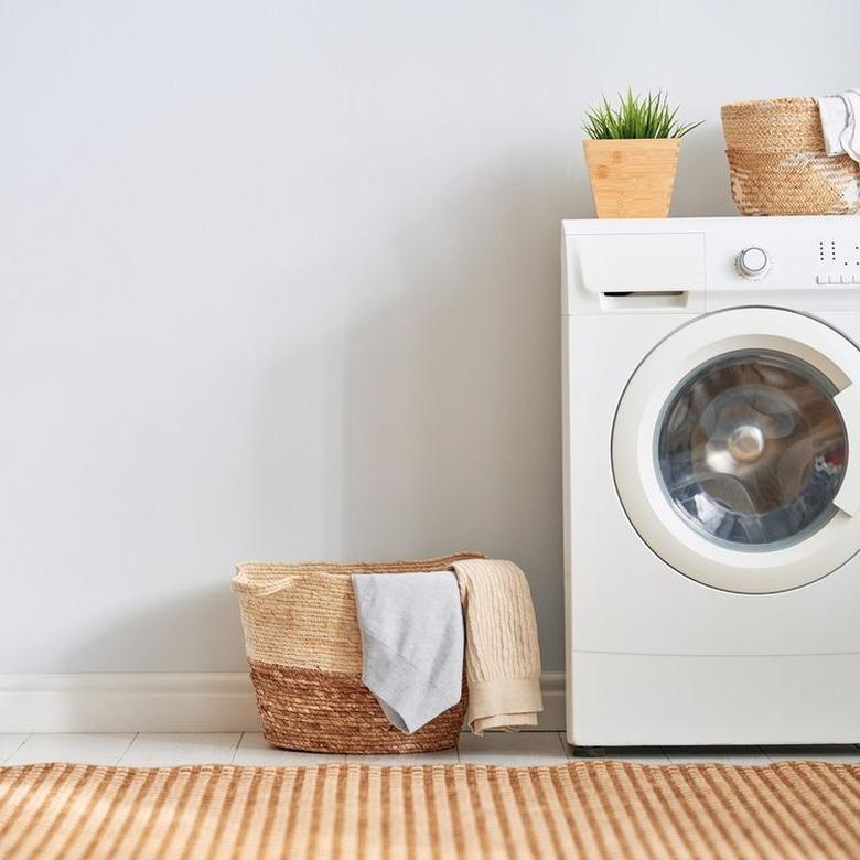 white washing machine next to wicker basket of laundry