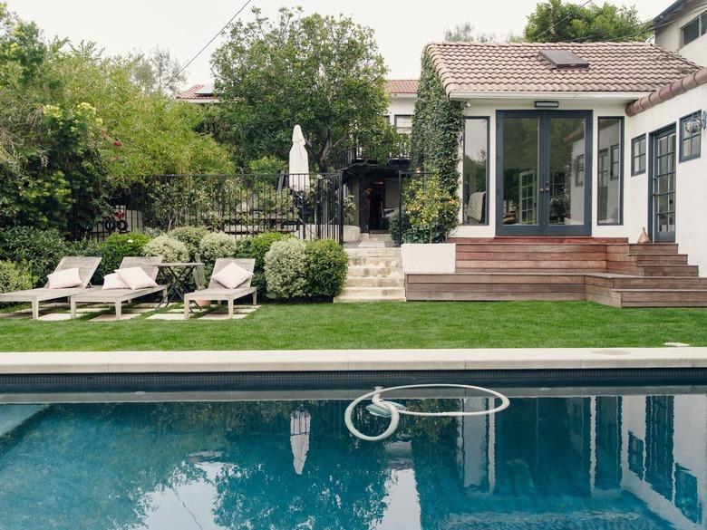 pool loungers on the lawn next to backyard pool