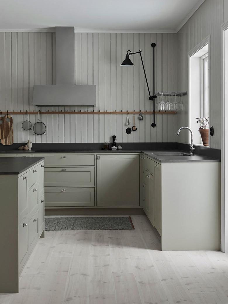 light wood kitchen floors with green cabinets by Nordiska Kok