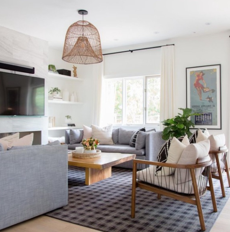 Living room with gray couches, accent chairs, rug, wicker chandelier.