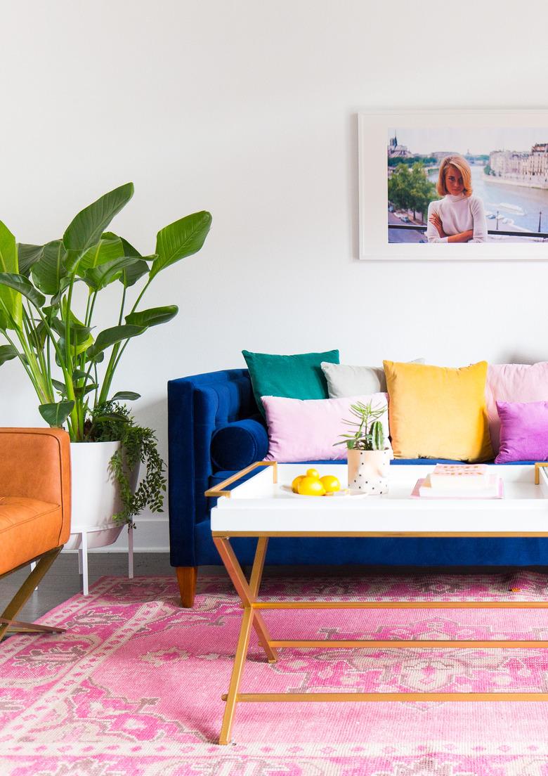 cool white living room makeover idea with pink rug and colorful sofa