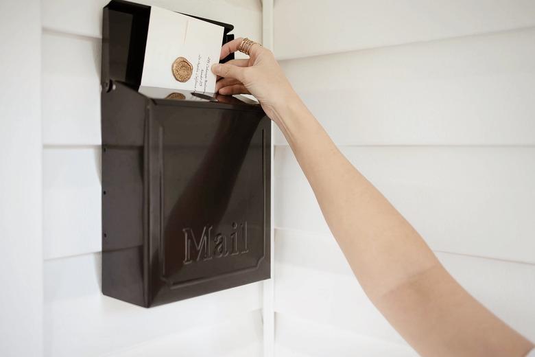 Black mailbox with hand adding letter