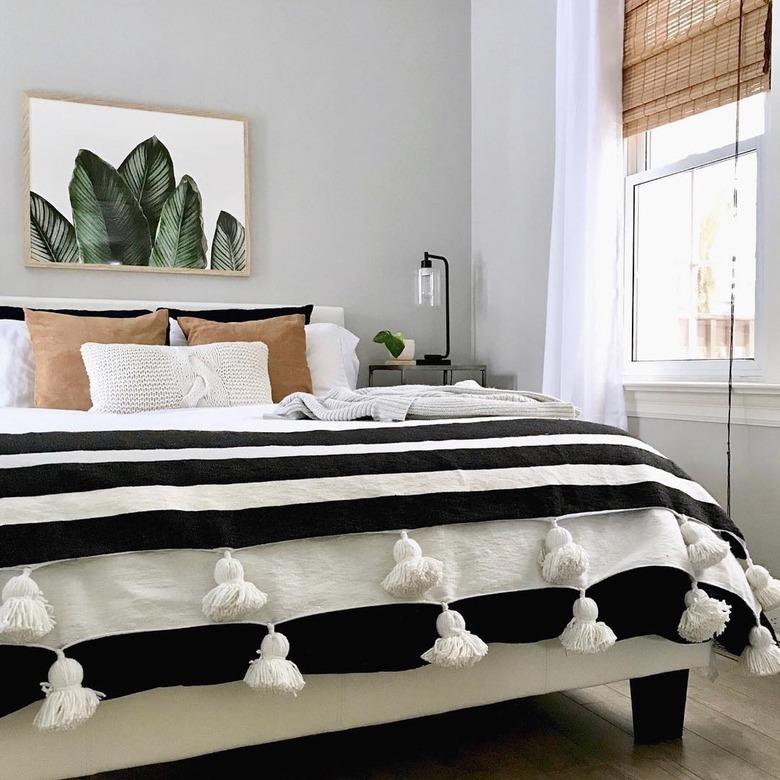 masculine boho bedroom with striped throw and plant artwork