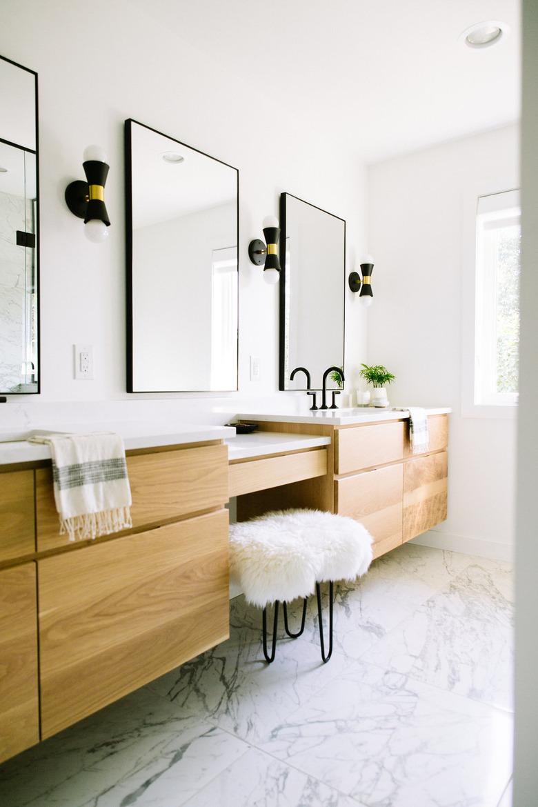 minimalist bathroom vanity with three large mirrors and a white stool.